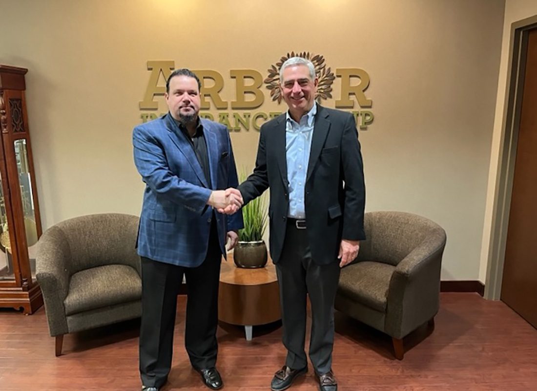 John F. Moore Agency - Portrait of Two Businessmen Dressed in Suits Shaking Hands in the Arbor Insurance Group Office to Celebrate Company Merger